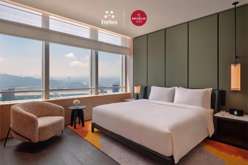 a bedroom with a large bed and a chair at Park Hyatt Changsha in Changsha