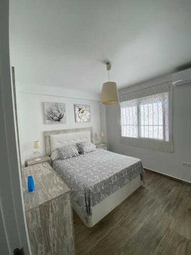a white bedroom with a bed and a window at La Terraza de María P in Torre del Mar