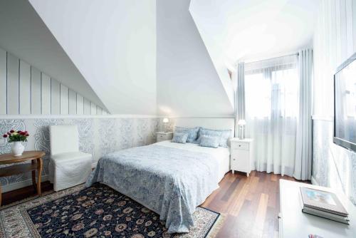a white bedroom with a bed and a table at Villa Victoria in Rydzewo