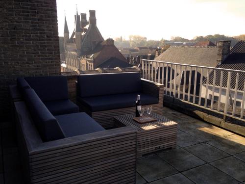 a balcony with a couch and a table with a bottle of wine at Atrium in Ypres