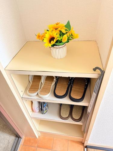a vase of flowers on a shelf with shoes at ひまわり in Dazaifu