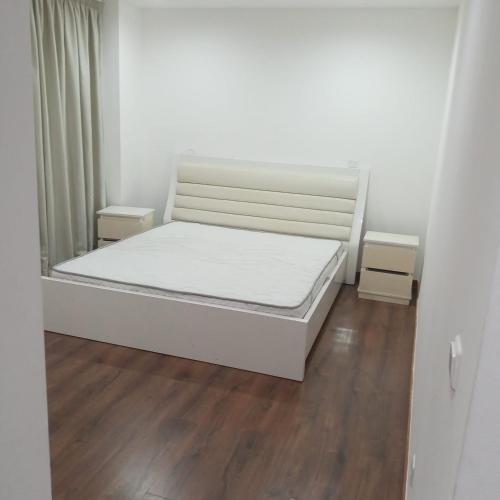 białe łóżko w pokoju z drewnianą podłogą w obiekcie Atlantic Terraces w mieście Luanda