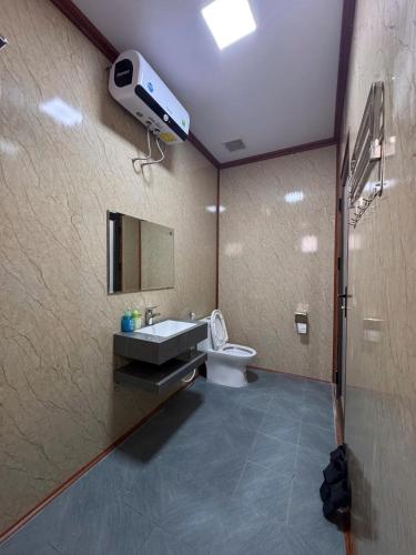 a bathroom with a sink and a toilet and a camera at Bình An Mountain Side Bungalow in Nguyên Ngoại