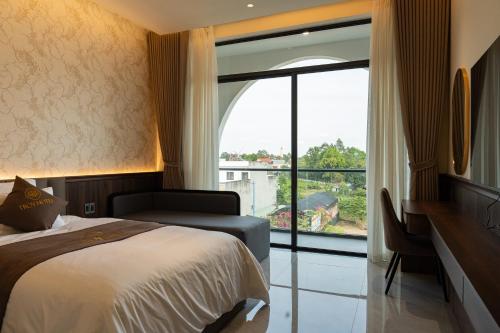 a bedroom with a bed and a large window at TROY HOTEL - Bà Rịa in Ấp Long Kiên I