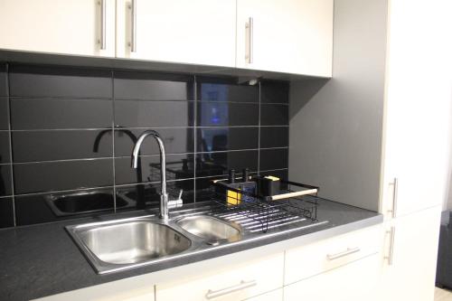 a kitchen with a stainless steel sink and black tiles at Apartment in MediaCity in Manchester