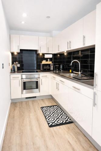a white kitchen with white cabinets and a sink at Apartment in MediaCity in Manchester