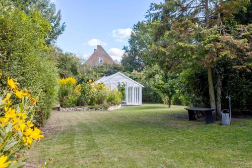a garden with a white greenhouse and a bench at Lovely appartment in charming town house in Assens