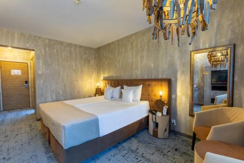 a bedroom with a large white bed and a chandelier at Alpin Resort Hotel in Poiana Brasov