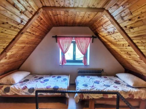 two beds in a attic room with a window at Holiday House - Hidden in Velebit in Senj