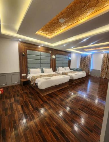 a bedroom with two beds and a wooden floor at Hotel Town Star in Srinagar