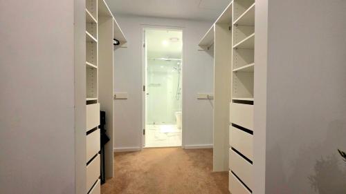 a walk in closet with white shelves and a door at Bliss in City in Canberra