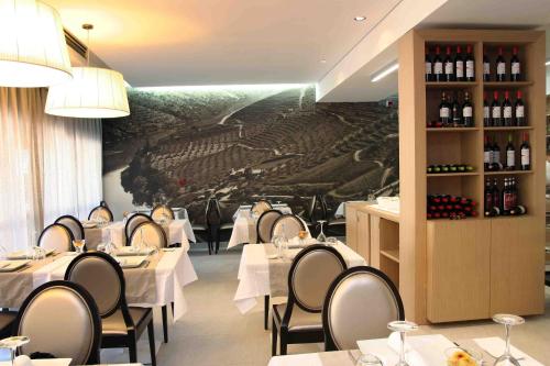 un restaurante con mesas y sillas blancas y un mural en Hotel Douro Inn en Tabuaço