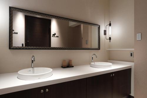 a bathroom with two sinks and a large mirror at ホテル風の山 in Iida