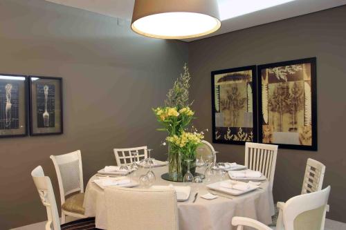 a dining room with a table with white chairs at Hotel Douro Inn in Tabuaço