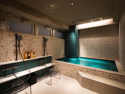 a swimming pool in a bathroom with green tiles at R Hotel RE Osaka Nagai Park in Osaka