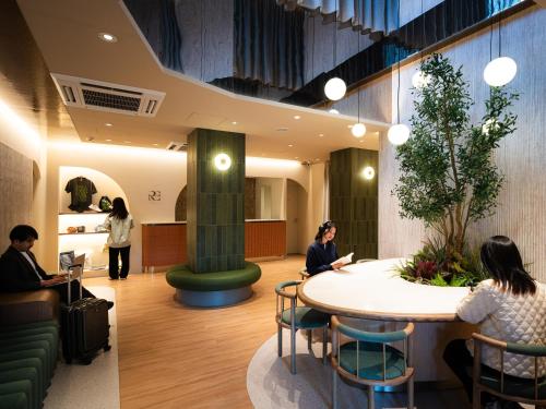 a lobby with people sitting around a round table at R Hotel RE Osaka Nagai Park in Osaka