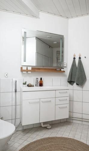 a white bathroom with a sink and a mirror at Tunnelmallinen saunallinen ullakkohuoneisto Ravintola Sampon yläkerrassa in Kuopio