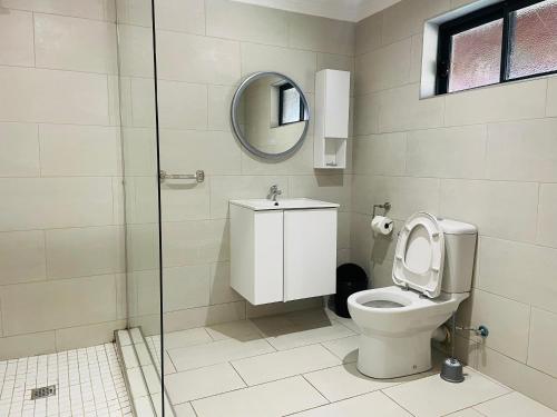 a bathroom with a toilet and a mirror at Amaryllis Residences Mount Pleasant in Blantyre