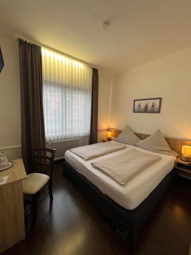 a bedroom with a bed and a desk and a window at Hotel Hüttl in Worms