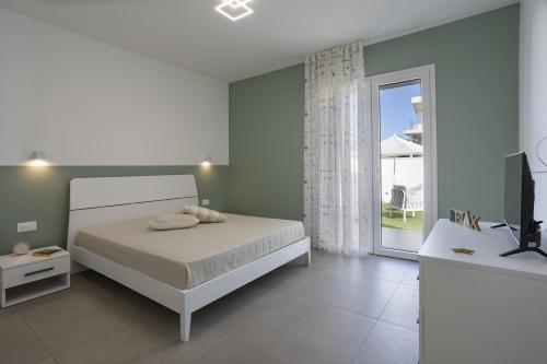 a white bedroom with a bed and a sliding glass door at Villa Nidea in Ragusa