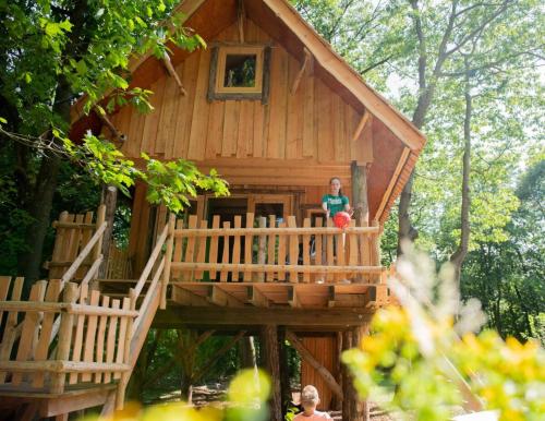 a woman standing on the stairs of a tree house at Wooden Lodge I Boomhut op Recreatiepark Mastendol in Rijen