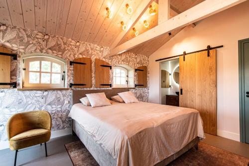 a bedroom with a large bed and a chair at B&B De NieuwenHof 'De Voorkamer' in Melderslo
