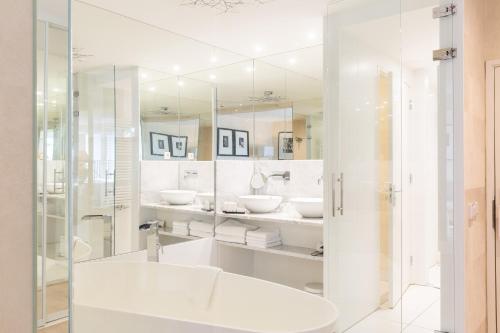 a white bathroom with two sinks and a mirror at Restaurant Hotel Merlet in Schoorl