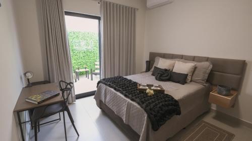 a bedroom with a bed and a table and a window at Jahu Center Casas Un 8 in Jaú