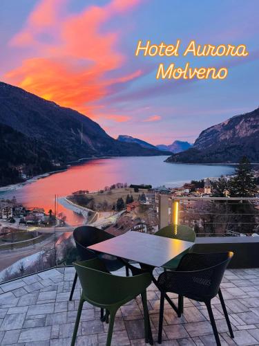 a table and chairs on a balcony with a view of a lake at Hotel Aurora in Molveno