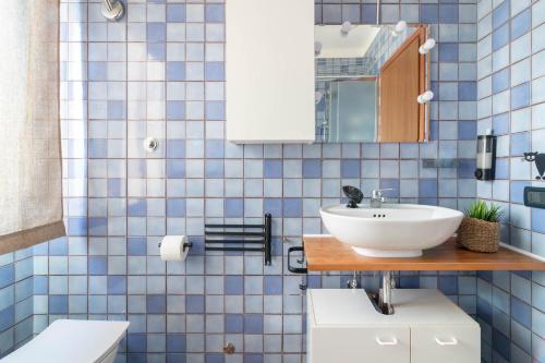 a blue tiled bathroom with a sink and a toilet at Ca Correr 326 in Cittadella