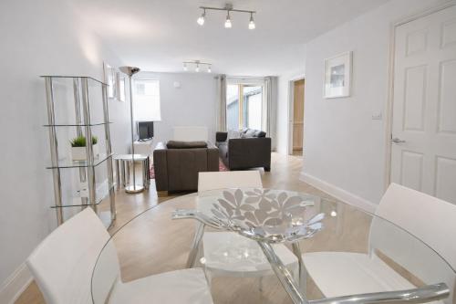 a white living room with a glass table and chairs at Roomspace Serviced Apartments - The Courtyard in London