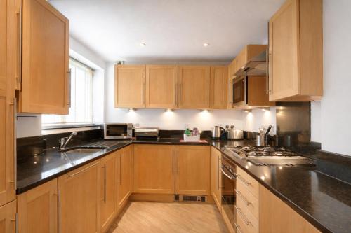 a kitchen with wooden cabinets and black counter tops at Roomspace Serviced Apartments - The Courtyard in London