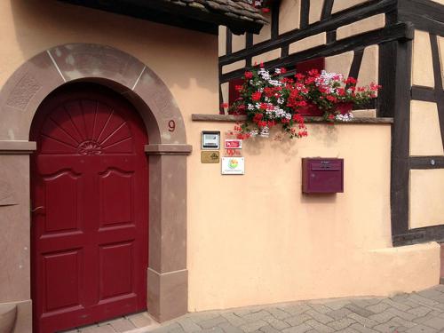 フェンデンハイムにあるLa Cour des Amisの花の建物側の赤い扉