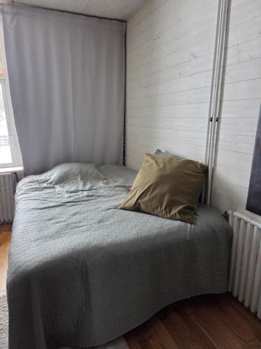 a bed with a gray blanket and a pillow at Blomstermåla in Blomstermåla