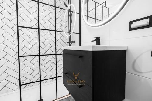 a black and white bathroom with a sink and a shower at Stag & Stay- Waterlillie - Contractor friendly, Fast WiFi in Port Glasgow