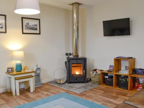 a living room with a wood stove in a room at Porthole Cottage in Allonby