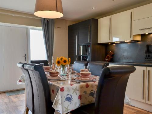 a kitchen with a table with chairs and a tablecloth on it at Porthole Cottage in Allonby