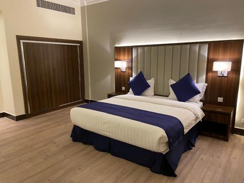 a bedroom with a large bed with blue pillows at بيست ليفل للشقق المخدومة in Al Khobar