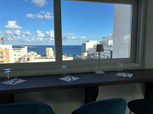 a table with a view of the ocean from a window at Stillel Retreat Suites in St. Paul's Bay
