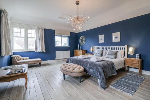 a bedroom with blue walls and a bed and a couch at Holly Lodge in Aldeburgh