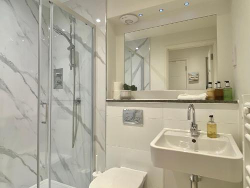 a white bathroom with a sink and a shower at Your Space Apartments - Cambridge Place in Cambridge