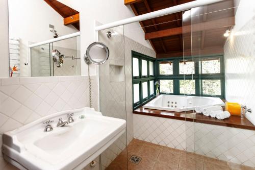 a white bathroom with a tub and a sink at Pousada do Quilombo in São Bento do Sapucaí