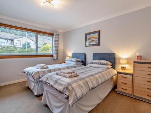 a bedroom with two beds and a dresser and a window at 2 Bed in Killin oc-pe512 in Killin