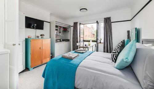 a bedroom with a large bed with blue pillows at Ferryman Studio Apartments in Portsmouth