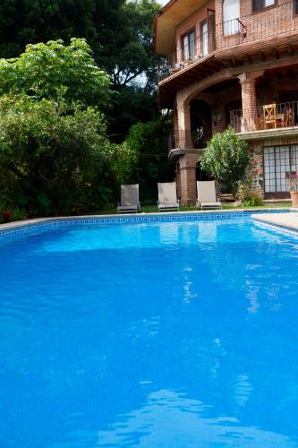 a large blue swimming pool in front of a house at Hotel Casa del Angel in Tepoztlán