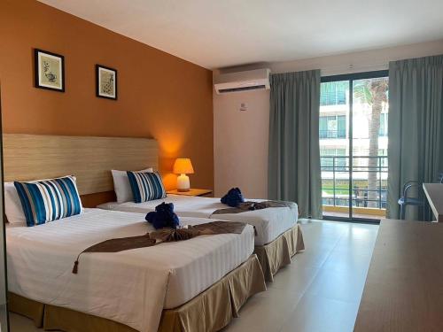 a hotel room with two beds and a window at Vogue Pattaya Hotel in Pattaya