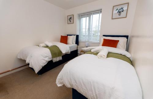 a bedroom with two beds and a window at Vantage Stays in Gloucestershire