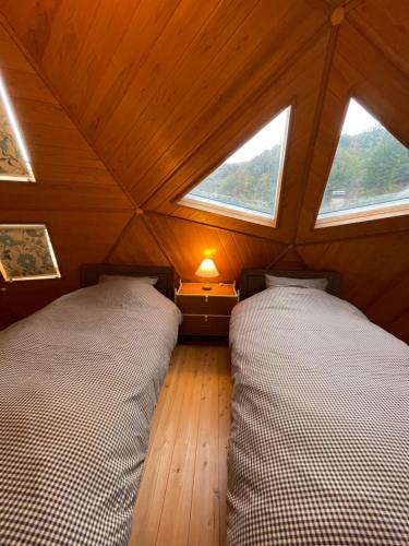 two beds in a small room with two windows at ゲストハウスフォレ in Kukumo