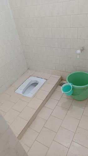 a bathroom with a toilet and a green bucket at Ganga Homestays in Tiruvannāmalai