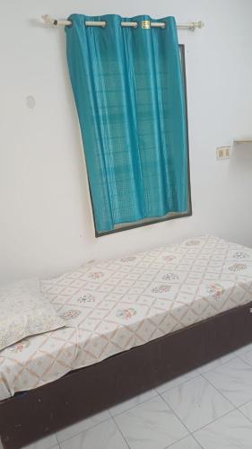 a bed in a room with a blue curtain at Ganga Homestays in Tiruvannāmalai